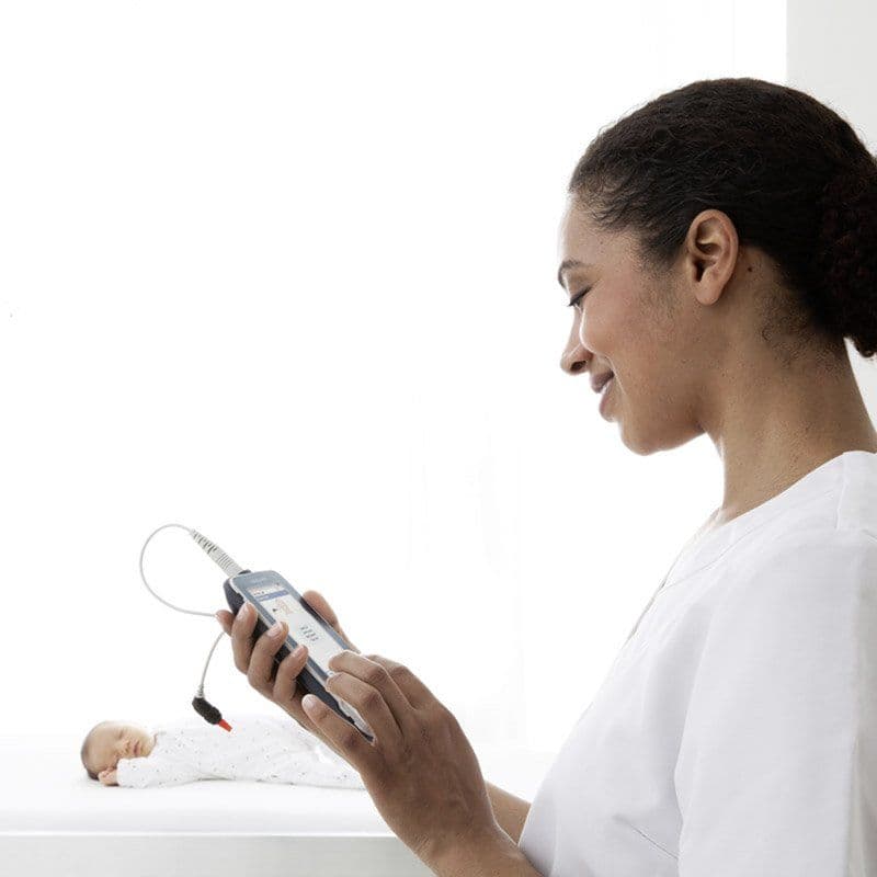 A healthcare person looking at a MAICO easyScreen while baby is sleeping in the background